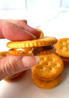 a hand holding a cracker over some crackers