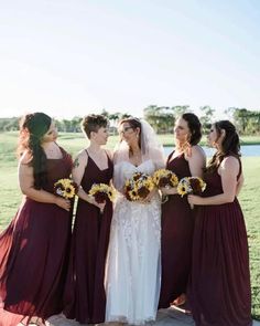 a group of women standing next to each other in front of a grass covered field