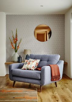 a living room with a blue couch and orange throw pillows on the floor next to a round mirror