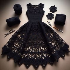 the dress is made up of black crocheted lace and has several knitting tools