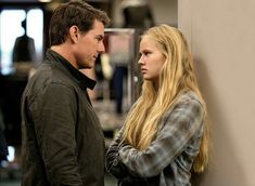 a man and a woman standing next to each other in an office building looking at each other