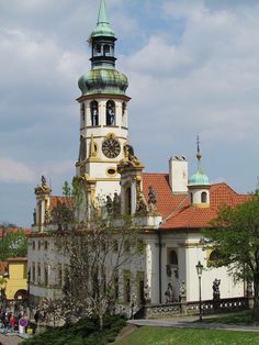 an old building with a clock tower on top and people walking around the yard in front