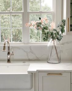 a vase with flowers in it sitting on a kitchen counter next to a white sink