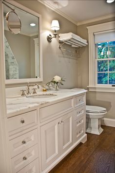 a bathroom with two sinks and a toilet next to a large mirror on the wall