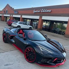 a black and red sports car parked in front of a building