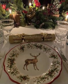 a white table topped with a plate covered in deer and pine cones next to candles