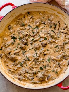 a red skillet filled with mushrooms and gravy on top of a table