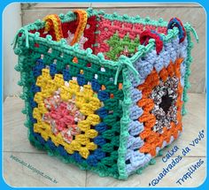 a colorful crocheted basket sitting on top of a white tile floor next to a blue frame