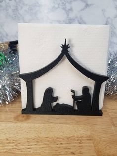 the nativity scene is made out of paper and has black silhouettes on it