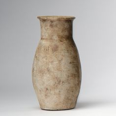 a white vase sitting on top of a table next to a gray wall and floor