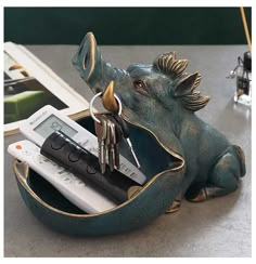 an elephant figurine holding keys and remotes in it's mouth on a table