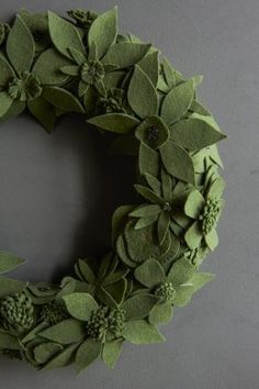 a wreath made out of green leaves and flowers on a gray surface with the word love written in it