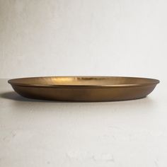 a gold plate sitting on top of a white counter next to a black bowl with handles