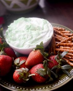 strawberries and pretzels on a plate with whipped cream in the bowl next to them