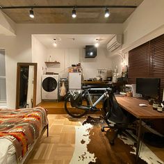 a bedroom with a bed, desk and bike on the floor in front of it