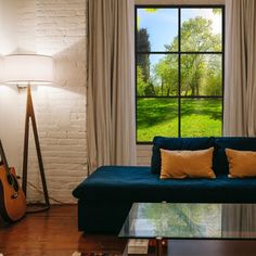 a living room with a couch, table and guitar in front of a large window