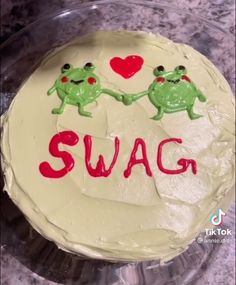 a cake with two green frogs holding hands and the words swag written on it