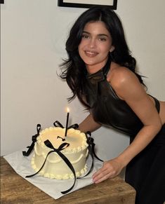 a woman is posing next to a cake