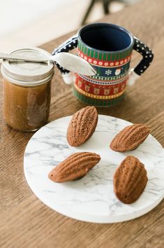 three almonds on a plate next to a jar of peanut butter