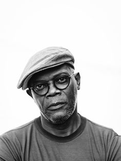 a black and white photo of a man wearing glasses, a hat and a t - shirt