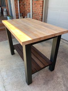 a wooden table sitting on top of a cement floor next to a garage door and brick wall