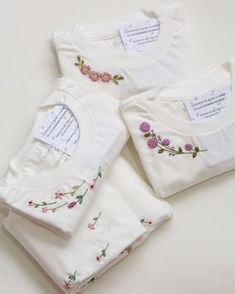 three white t - shirts with embroidered flowers on them