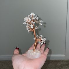 a woman's hand holding a small crystal tree