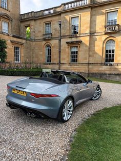 a grey sports car parked in front of a large building