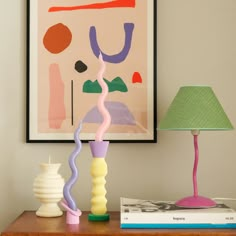 a table with two lamps and a painting on the wall