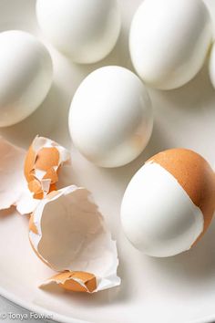 an egg is broken in half on a white plate with other eggs around the edge