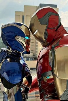 two iron man suits standing next to each other in front of a cityscape