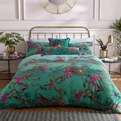 a bed with green and pink comforters in a room next to a planter