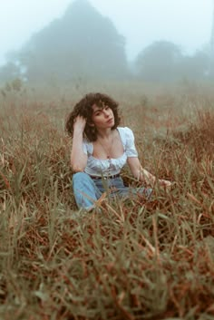 a woman sitting in the middle of a foggy field