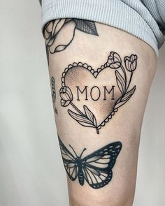 a woman's leg with a butterfly and heart tattoo on it that says mom