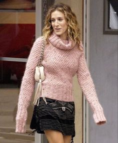 a woman is walking down the street wearing a pink sweater and black miniskirt