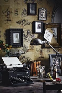 an old fashioned typewriter sitting on top of a wooden table next to framed pictures