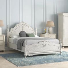 a white bed sitting on top of a wooden floor next to a dresser and mirror