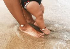 a person standing on top of a sandy beach next to the ocean with their feet in the water