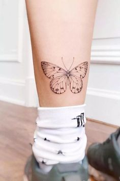 a small butterfly tattoo on the ankle is shown in black and white colors, with stripes around it