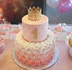 a pink and white cake with a gold number one on top sitting on a table