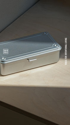 a metal box sitting on top of a wooden table next to a window sill