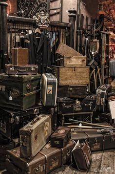 a pile of luggage sitting on top of a wooden floor next to a cage filled with suitcases