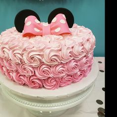 a minnie mouse cake with pink frosting and white polka dots on top, sitting on a table