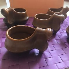 four brown bowls sitting on top of a purple mat