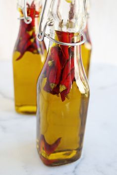 two glass bottles filled with flowers sitting on top of a white marble countertop next to each other