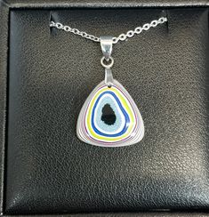 This necklace is made from semi truck fordite from Ohio. It's in a top domed triangle with a flat back. This is a nicely sized piece with great color and patterns.The bail that secures the fordite and the included 20 inch chain are stainless steel. The fordite measures about 19 mm tall. See the pictures for scale next to a nickel. Necklace holder not included. Fordite is recycled automotive paint sourced from automotive factories as well as manufacturers who paint parts for new vehicles. It forms in thin layers as car parts are painted on the racks that hold them in place. After hundreds of trips through the booth where the paint is sprayed and then baked the excess buildup is scraped off the racks. We buy this waste paint in rough chunks and recycle it into beautiful jewelry. It can take Artisan Jewelry Necklaces, Automotive Paint, Necklace Holder, Vehicle Paint, Semi Truck, Handcrafted Artisan Jewelry, Semi Trucks, Car Manufacturers, Artisan Jewelry