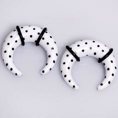 two white and black polka dot hair clips on a gray background, one is shaped like a crescent