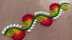 a close up of an embroidered design on a cloth material with green and red swirls