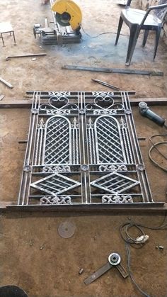 an iron grate sitting on top of a floor next to some chairs and tools