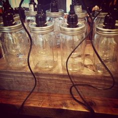 four mason jars with black lids are sitting on a wooden table and one is plugged into a charger